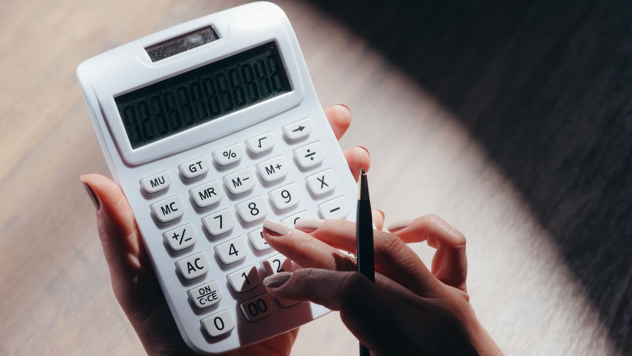 Mastering the First Impression: Your intriguing post title goes here Hands holding a calculator and pen for financial calculations in a well-lit setting.